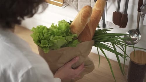 Una joven europea llevó a la cocina una bolsa ecológica de papel con verduras frescas, hierbas y baguette