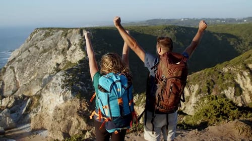 Couple of Tourists with Camping Backpacks Standing at Cliff