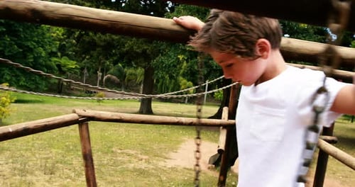 Boy walking on a playground ride in park