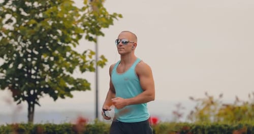 Man Jogging Through Urban Park on Cloudy Day