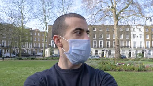 Young man portrait with face mask on - Man wearing a medical mask at park in