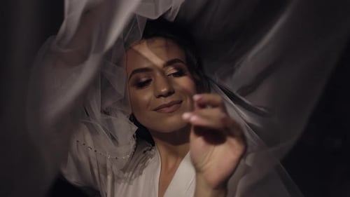 Woman Poses with Wedding Veil in Dark Room