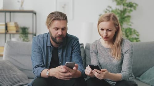 Blond Woman and Man on Couch Looking at Phones