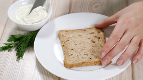 Spreading Cream Cheese on Wheat Bread for Snack