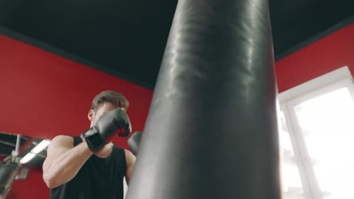Athletic Man Punching Heavy Bag in Gym