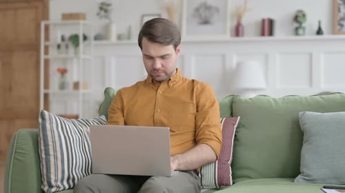 Man Typing on Laptop Computer on Green Couch