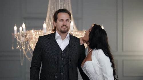 Elegant Couple Smiling Together Beneath Chandelier