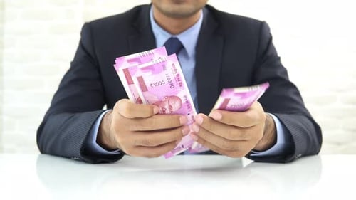 Businessman counting money, Indian ruupee banknotes, at the table