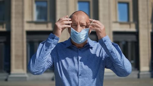 Adult Putting on Medical Mask in Urban Setting