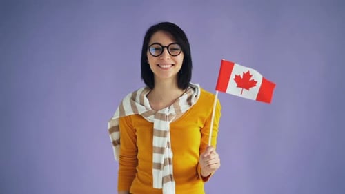 Smiling Woman Holding Small Canadian Flag Indoors