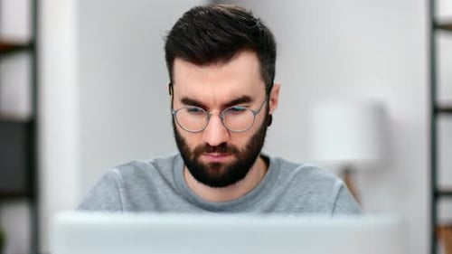 Closeup Confident Man in Eyeglasses Working Laptop Browsing Internet at Modern Home Office