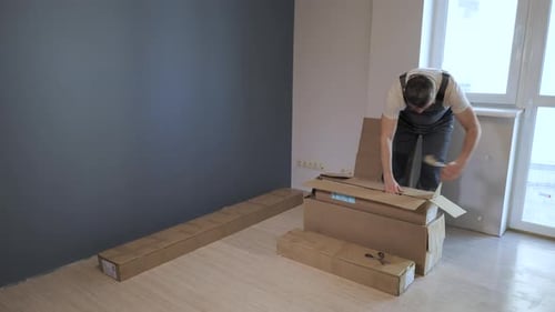 Man unpacking boxes of material in bright room