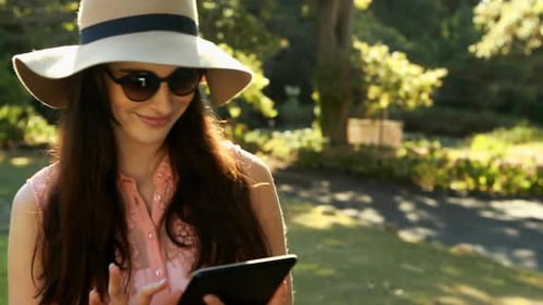 Woman using digital tablet in park