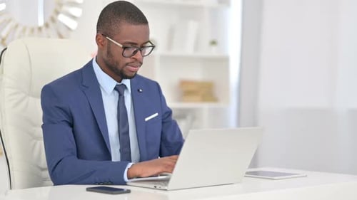 Attractive Young African Businessman Working on Laptop in Office