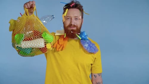 Man With Recycled Garbage Holding Bag of Plastic