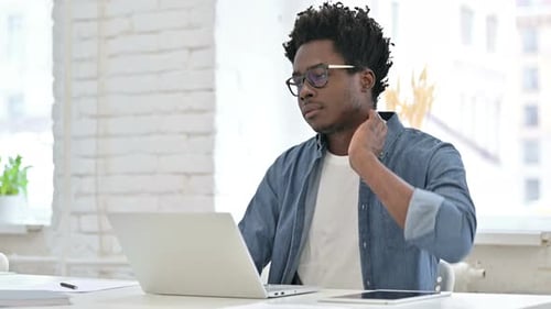Man Stretches Neck While Working on Laptop