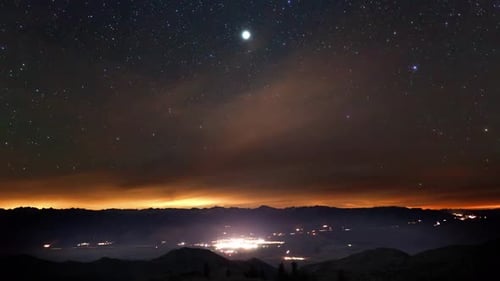 Starry Night Sky Over Mountains and Distant Town