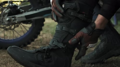 Mains de motocyclistes attachant des sangles aux bottes d'équitation