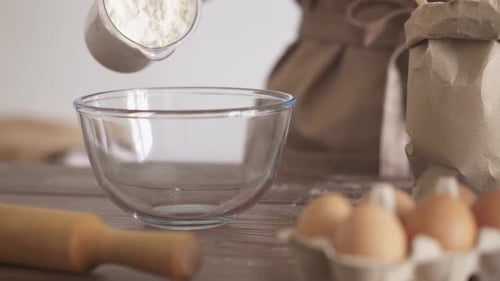 Den Teig kneten. Der Koch gießt das Mehl aus einem Messglas in eine durchsichtige Schüssel