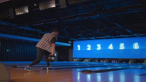 Kaukasischer Mann im Bowling wirft einen Ball in Zeitlupe und schlägt Kegeln nieder
