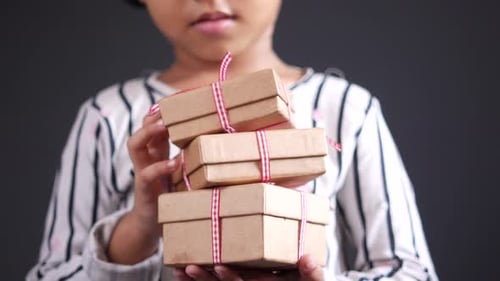 Child Holds Stack of Wrapped Birthday Gifts