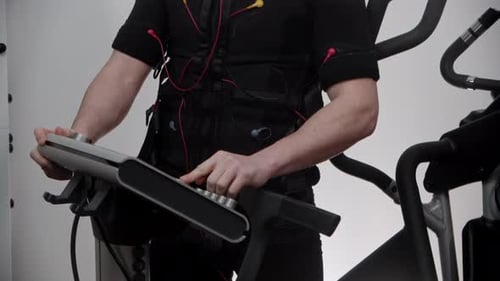 Hübscher Mann im Ems-Anzug schaltet die Stimulation ein und beginnt mit dem Training