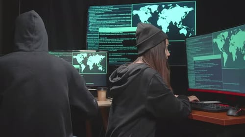 Vue arrière d'un jeune couple asiatique de pirates informatiques utilisant le piratage informatique et le code sur plusieurs écrans d'ordinateur