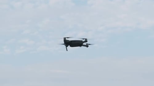 Drone Hangs in the Air Against the Blue Sky, View From Below. Slow Motion