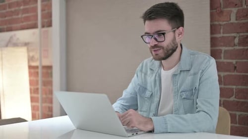 Man Video Conferencing on Laptop in Office