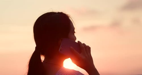 Woman Talking on Phone at Beautiful Golden Sunset