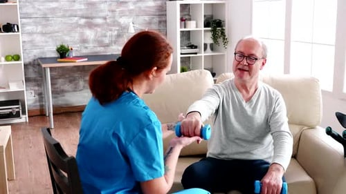 Caucasian Caregiver in Nursing Home Helping an Old Man to Recover Muscle Strength