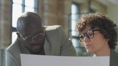 Caucasian Woman Discussing Paper with Black Male Colleague