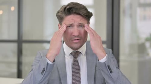 Stressed Businessman Experiencing Headache at Work