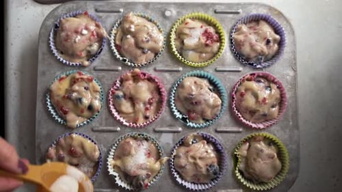 Person adds Sugar to Fruit Muffin Batter
