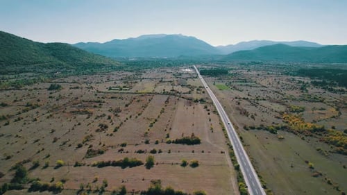 Aerial View Empty Asphalt Road on the Plateau Between Green Fields Highland Way