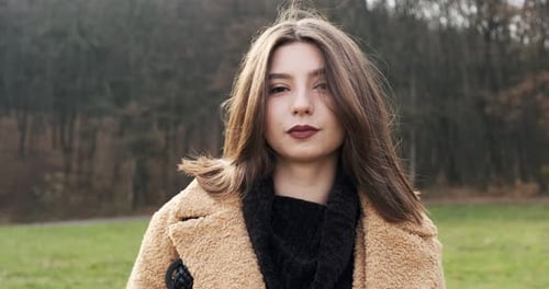 Portrait of Young Attractive Female Who Smiling and Looking at the Camera on Green Lawn. Cheerfully