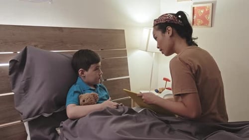 Woman Reading Bedtime Story to Boy in Bed