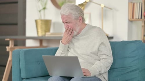 Senior Man Coughing While Using Laptop at Home