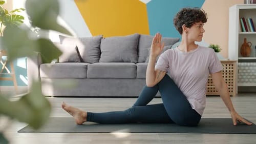 Woman Practices Yoga Twists for Fitness Indoors