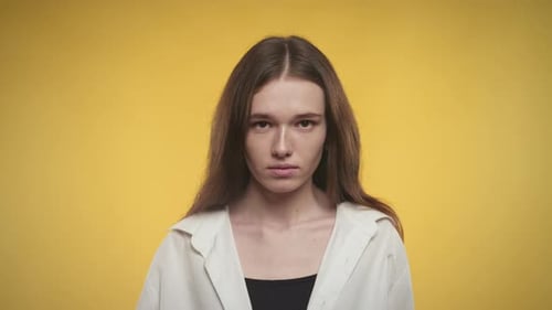 Young Woman Stares Seriously at Camera on Yellow