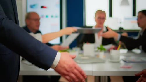 Close Up of Multiracial Business Partners Standing in Front of Conference Desk Shaking Hands