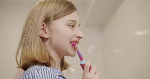 Girl Brushing Teeth with Pink Electric Toothbrush
