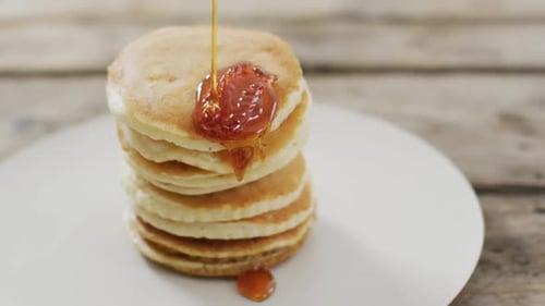 Video von Pfannkuchen mit Ahornsirup auf weißem Teller von oben