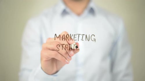 Person Writes Marketing Strategy on Clear Surface
