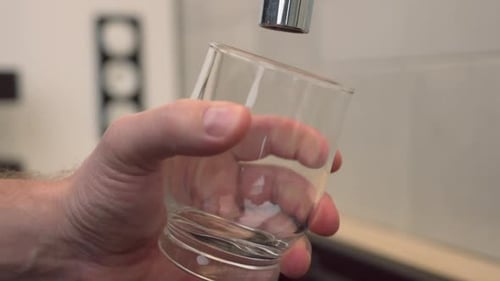 El hombre vierte un vaso de agua