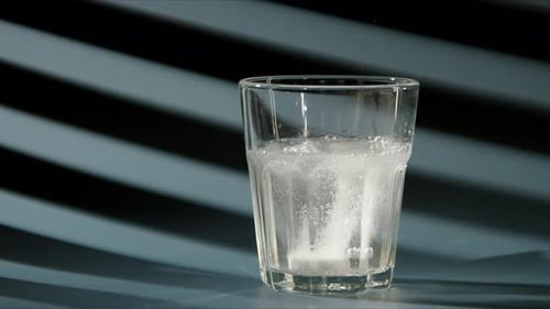Effervescent Tablet Falls Into a Glass with Clear Clear Water