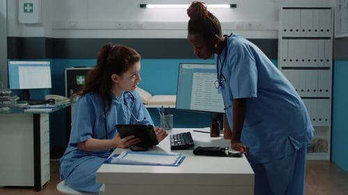 Multi Ethnic Team of Nurses Looking at Tablet and Talking About Healthcare