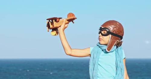 Glückliches Kind spielt mit Spielzeugflugzeug vor dem Hintergrund von Meer und Himmel