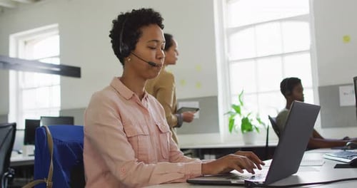 Woman Working at Laptop with Headset in Office