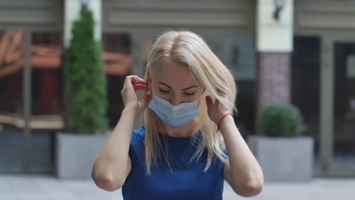 Woman Puts on Surgical Mask Outdoors in the City